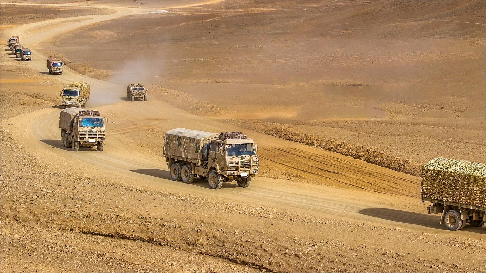 Military trucks maneuver through desert