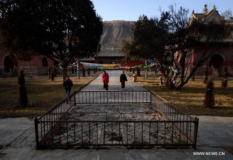 Lamas and a tourist walk at the Qutan Temple in Ledu County, northwest China's Qinghai Province, Nov. 10, 2012. The Qutan Temple of the Tibetan Buddhism started to be built in 1393 during ancient China's Ming Dynasty (1368-1644). (Xinhua/Wang Bo)
