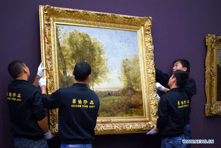 Working staff hand the masterpiece by Corot during the exhibition arrangement of "Millet, Courbet and French Naturalism: Masterpieces from Musee d'Orsay" at the China Art Meseum in east China's Shanghai, Nov. 12, 2012. (Xinhua/Ren Long) 