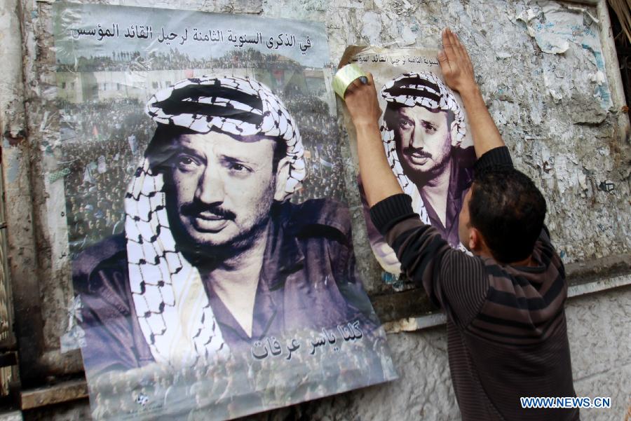 A Palestinian posts a poster showing late Palestinian leader Yasser Arafat in West Bank city of Nablus, on Nov. 11, 2012, marking the eighth anniversary of Arafat's death. (Xinhua/Nidal Eshtayeh)