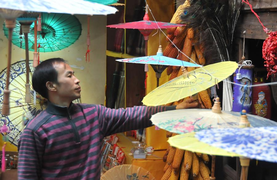 A craftsman views oil-paper umbrellas at a workshop in Xixiu District of Anshun City, southwest China's Guizhou Province, Nov. 12, 2012. Made of oiled paper and bamboo frame, oil-paper umbrella is a traditional Chinese handicraft. The skills of making oil-paper umbrellas were introduced to Guizhou in early Ming Dynasty (1368-1644). (Xinhua/Huang Yong) 