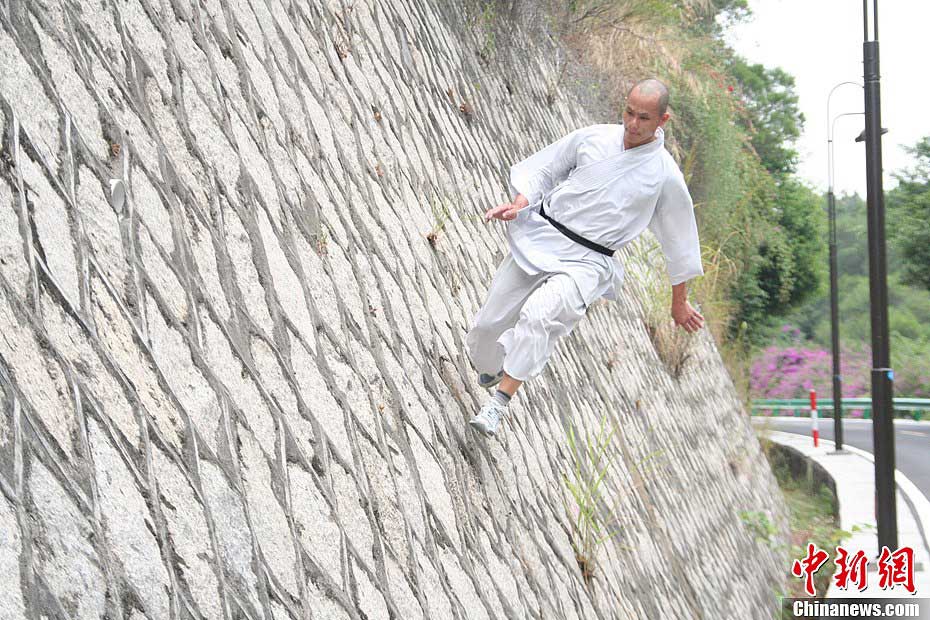 Shi Liliang, a monk from Southern Shaolin Temple, performs a Chinese martial art stunt by walking on a wall in Quanzhou, Fujian province, Nov 12, 2012. He "flies" on a 5-meter-high wall, breaking his previous walking record. He also mastered the well-known Chinese martial "Yizhichan" (One finger zen) and can run on water under thin plywood for about 45 meters. (CNSPHOTO/Su Qiaofeng)