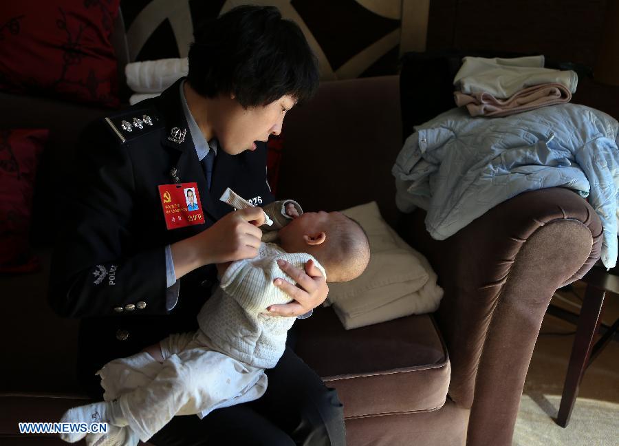 Jiang Min, a delegate to the 18th National Congress of the Communist Party of China (CPC), puts ointment on the face of her son, who had eczema, in Beijing, capital of China, Nov. 13, 2012.(Xinhua/Jin Liwang)