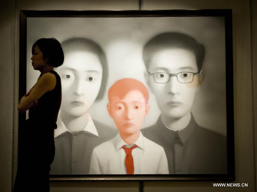 A staff member walks past an oil painting of Zhang Xiaogang on a press conference of the Christie's autumn auction preview event in south China's Hong Kong, Nov. 14, 2012. The auction will be held in Hong Kong from Nov. 24 to Nov. 28. (Xinhua/Lui Siu Wai) 