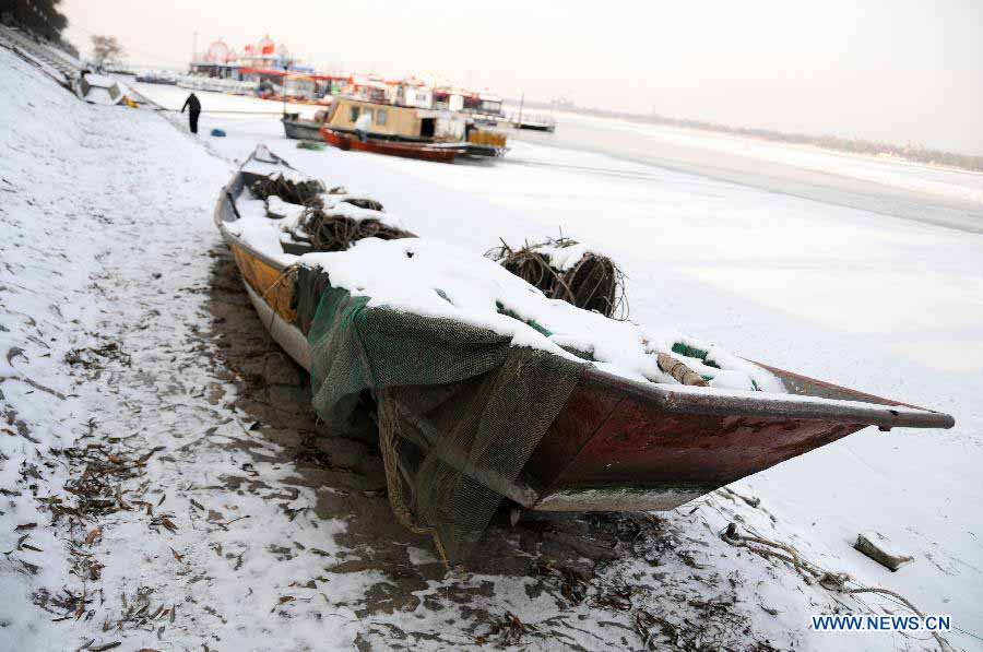 A snow-covered boat is seen at the bank of the frozen Songhua River in Harbin, capital of northeast China's Heilongjiang Province, Nov. 19, 2012. Navigation on the Harbin section of Songhua River has been closed since Monday, as the river entered frozen-up season due to the temperature plunge recently. (Xinhua/Wang Kai) 