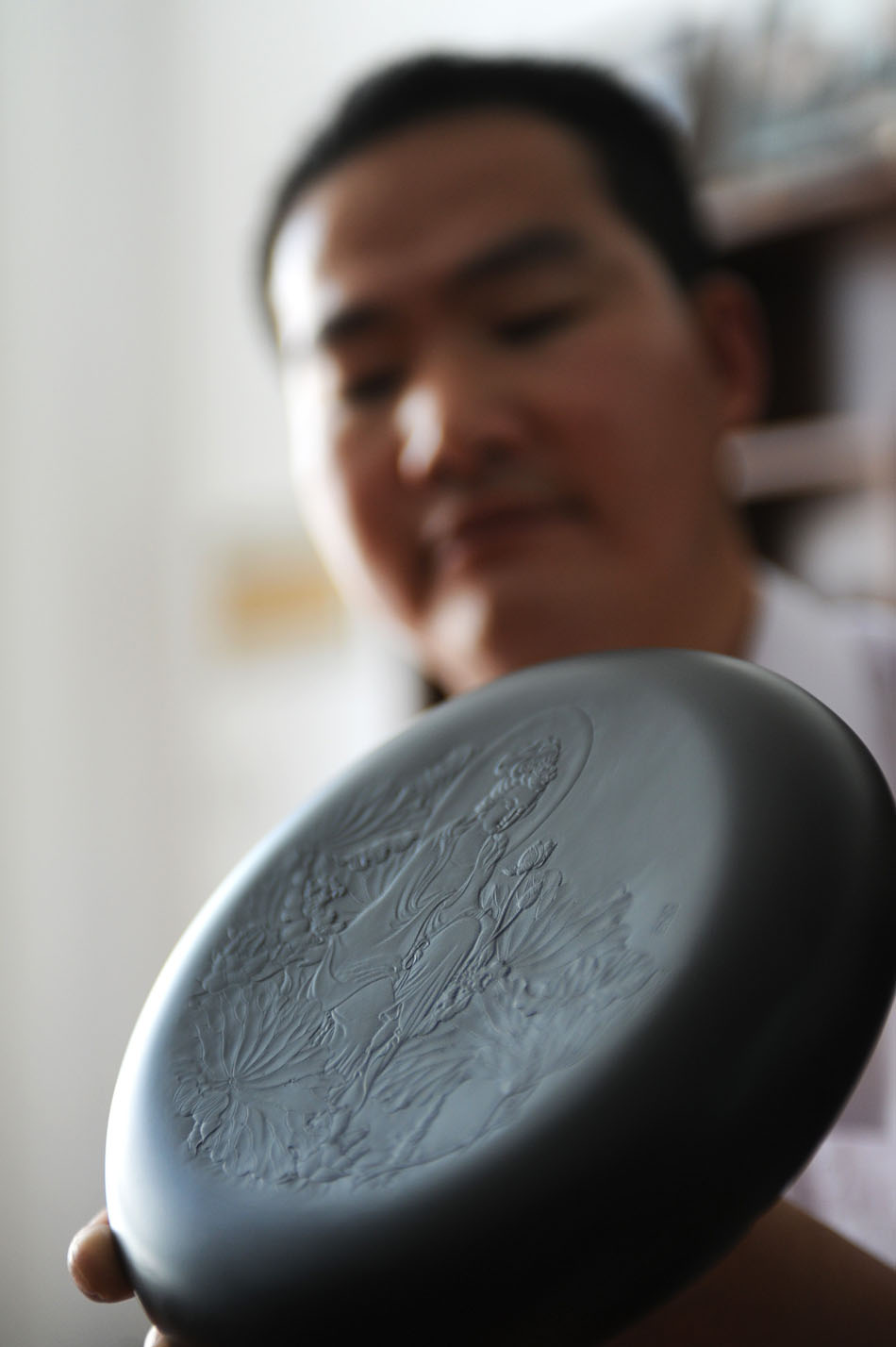 Wen Xin shows one of his inkstone carvings in Shexian County of east China's Anhui Province, Aug. 7, 2012. (Xinhua/Du Yu)