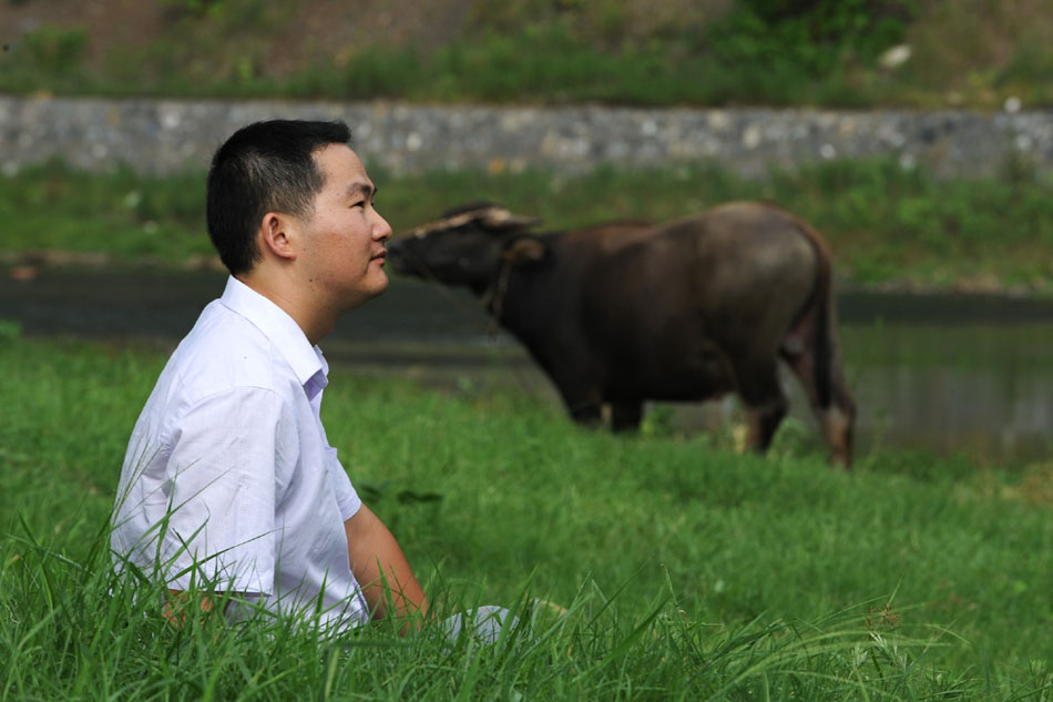 Wen Xin sits on the grass outside his studio in Shexian County of east China's Anhui Province, Aug. 7, 2012. (Xinhua/Du Yu)