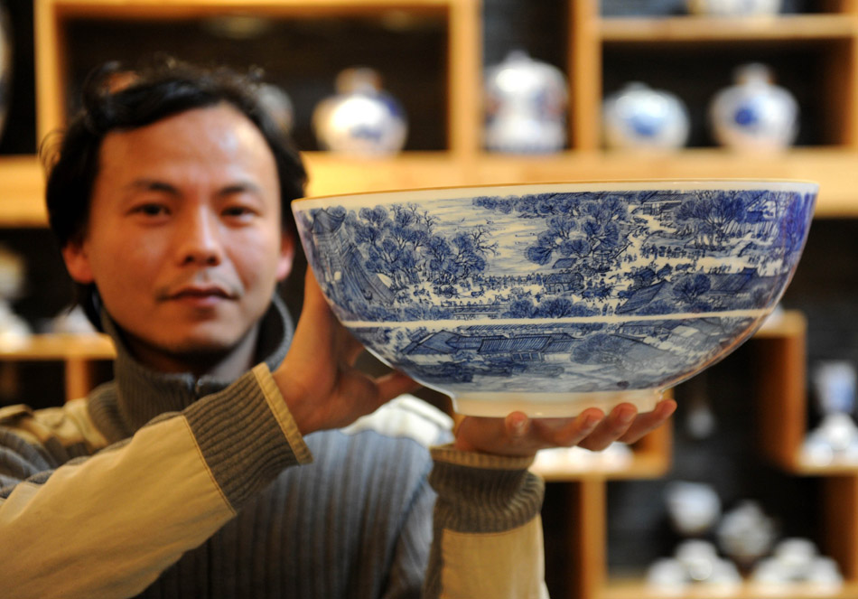 Liu Zhen shows the porcelain bowl "Riverside Scene at the Qingming Festival" in the Chengdexuan Porcelain Co.,Ltd, in Jingdezhen of east China's Jiangxi Province, March 8, 2012. The thickness of the bowl is 0.4 millimeter and it took him half a year to finish painting. (Xinhua/Zhou Ke)