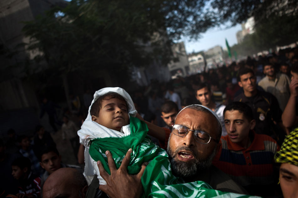 A Hijazzi family member holds the body of Hijazzi's son during a funeral in Gaza City, Nov. 20, 2012. Israeli fighter jets hit a house in northern Gaza Strip Monday evening, killing a father and two sons and wounding 12 others, witnesses and medical sources said. The house in Beit Lahiya town was destroyed while the father, Fouad Hijazzi, died along with his two sons, aged four and two respectively. (Xinhua/Chen Xu) 
