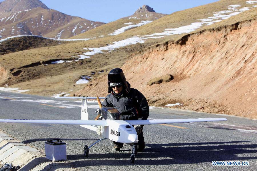 A technicist from the Shandong Electric Power Research Institute (SEPRI) examines an unmanned aircraft which is designed to inspect power transportation lines in regions of high altitude, during a test in Qinghai, a province on the Qinghai-Tibet Plateau, northwest China, Nov. 20, 2012. A research team of the SEPRI has recently conducted a flight test of unmanned aircrafts over the ground with altitude of 4,500 meters, which marks the end of the first round of the unmanned aircraft test project for inspecting power transportation lines on plateaus. (Xinhua)