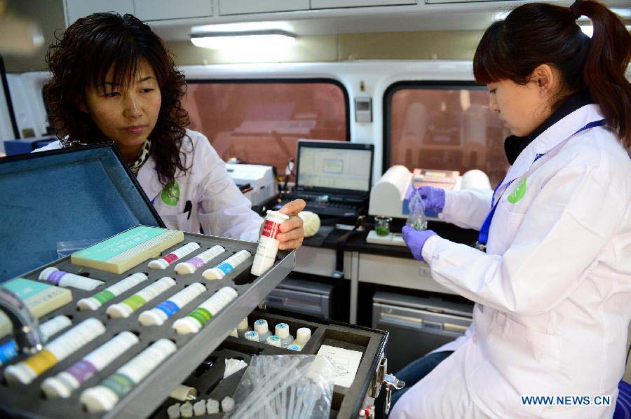 Two researchers conduct food test in the newly-developed intelligent vehicle for food detection in Lanzhou, capital of northwest China's Gansu Province, Nov. 21, 2012. The intelligent vehicle can conduct various kinds of food tests on site. (Xinhua/Zhang Meng)