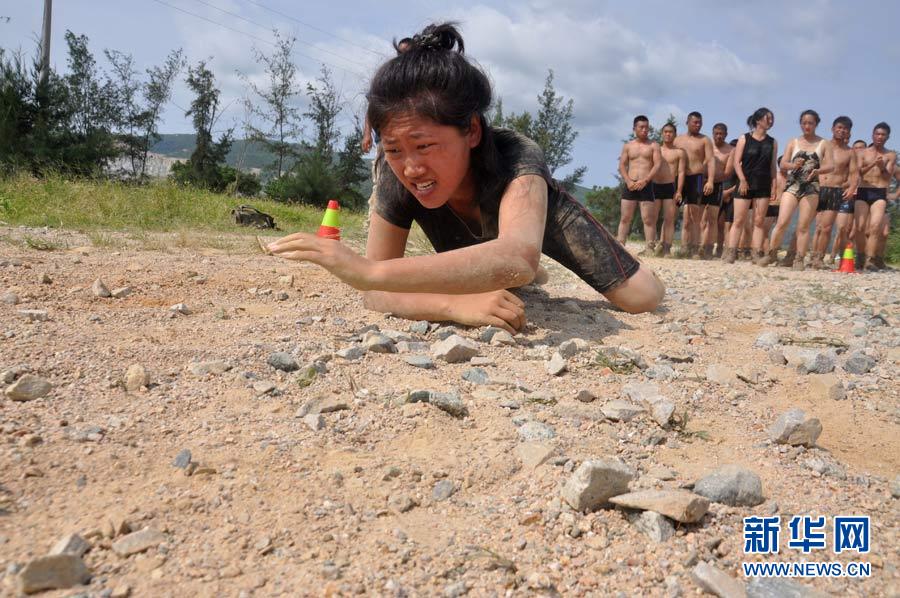 A female trainee crawling over the ground covered with sharp gravel. (Xinhua/Liu Changlong)