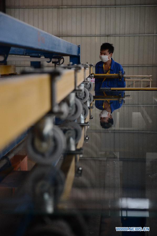 A man works on the production line in Hongyu energy company in Zhangshu, east China's Jiangxi Province, Nov. 22, 2012. The company has invested 350 million yuan (56.1 million dollars) and built the largest energy efficiency glass production line in China. (Xinhua/Zhou Mi)