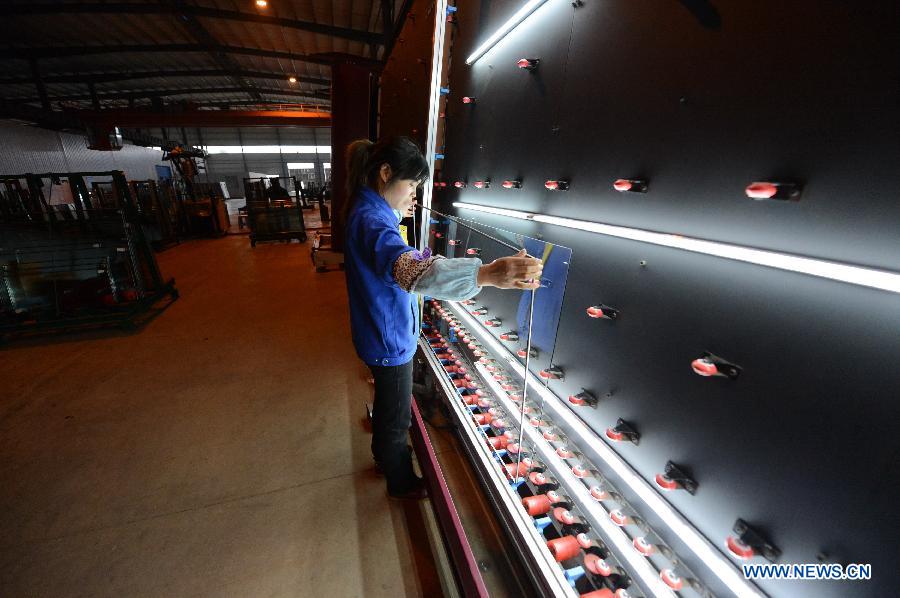 A woman works on the production line in Hongyu energy company in Zhangshu, east China's Jiangxi Province, Nov. 22, 2012. The company has invested 350 million yuan (56.1 million dollars) and built the largest energy efficiency glass production line in China. (Xinhua/Zhou Mi)