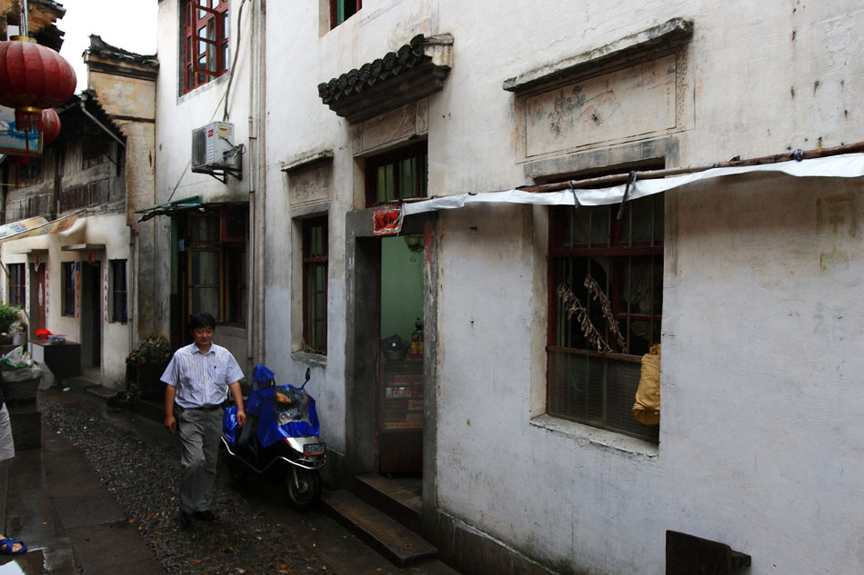 Xiang Shengli walks in an alley of Yuliang Village in Shexian County of east China's Anhui Province, Aug. 8, 2012. The paintings on the windows of nearby building was painted By Xiang in 1987. (Xinhua/Xu Zijian)
