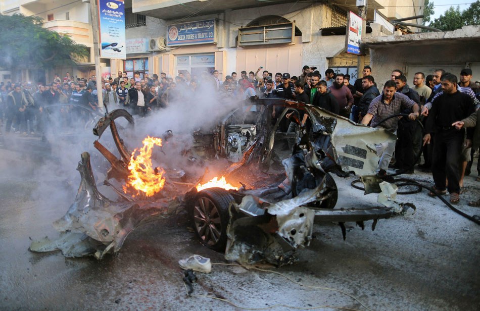 Emergency services extinguish the burned-out car of Qassam top leader Ahmed Jabari after an Israeli air strike in Gaza City, Nov. 14, 2012. (Xinhua/Wissam Nassar) 