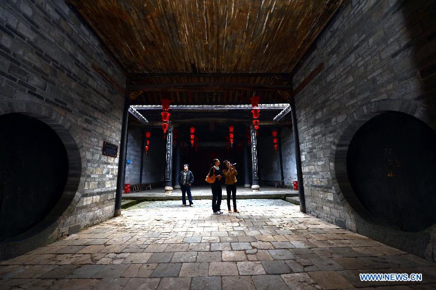Visitors travel around the ancestral hall of a walled village in Xinwei Village of Longnan County in Ganzhou City, east China's Jiangxi Province, Nov. 20, 2012. The Gannan (southern Jiangxi Province) Hakka walled villages, a special architectural type, was included into China's World Cultural Heritage Tentative List on Nov. 17, 2012. The whole structure of the building resembles a small fortified city, containing halls, storehouses and living areas. It is regarded as the "cradle of Hakka". According to official statistics, there are over 600 such buildings in Gannan at present. (Xinhua/Song Zhenping)