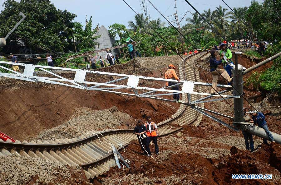 Staff members try to fix railway and electric wires broken in a landslide in Bogor, Indonesia, Nov. 22, 2012. Landslide caused by rainfall Wednesday night destroyed rails and led to the cancel of 98 flights. (Xinhua/Dwi)