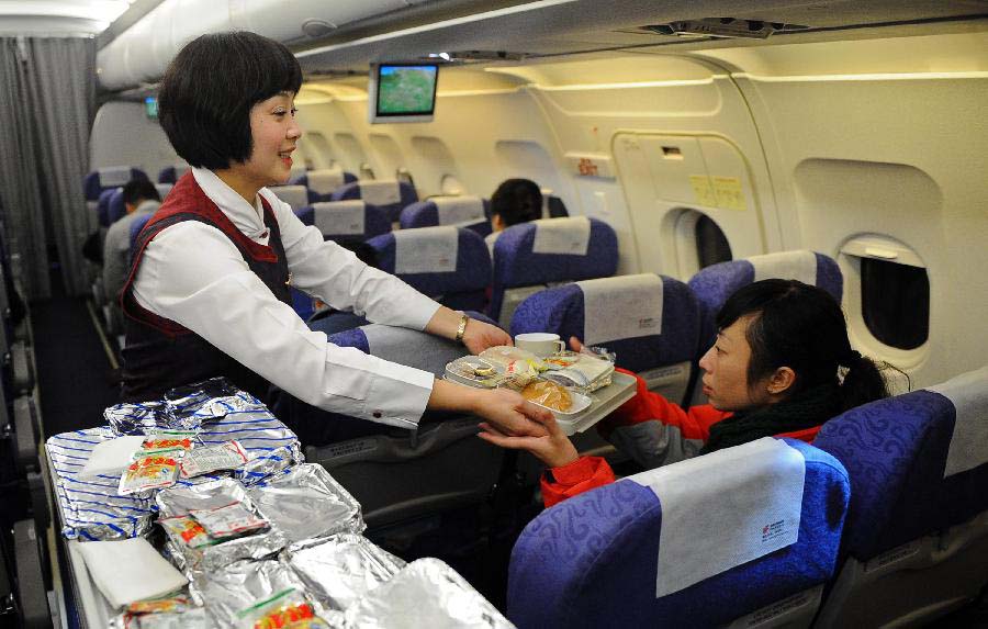 A stewardess serves passengers on the test flight to the Daochengyading Airport in Daocheng County of the Tibetan Autonomous Prefecture of Garze, southwest China's Sichuan Province, Nov. 23, 2012. The first test flight of the airport successfully landed Friday. With the height of 4,411 meters above sea level, the Daochengyading Airport becomes the highest civil airport in the world. (Xinhua/Xue Yubin) 