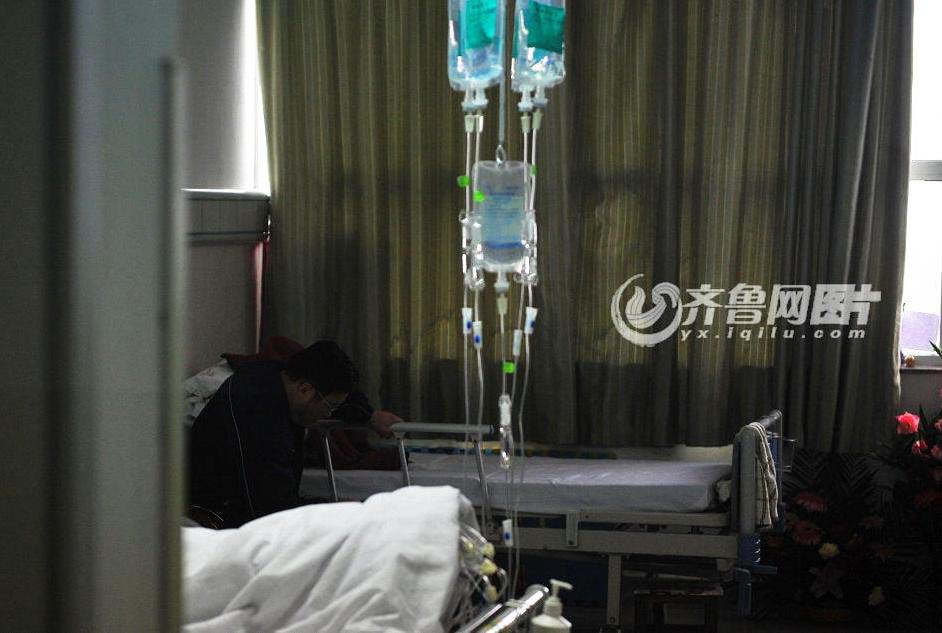 Gong Yuben’s father, Gong Guangyong keeps silence in front of his son’s bed. (iqilu.com/Zhang Xiaobo)