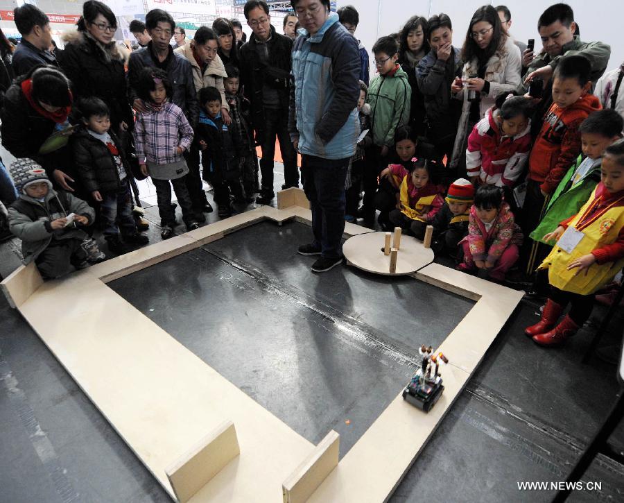 Visitors view a robot running in an obstacle avoidance test during a robot show held in Qingdao University, Qingdao, east China's Shandong Province, Nov. 25, 2012. The robot show, the first kind of this exhibition in Shandong, showcased the latest achievement of robot-related technology, involving over 100 exhibits from home and abroad. (Xinhua/Li Ziheng) 