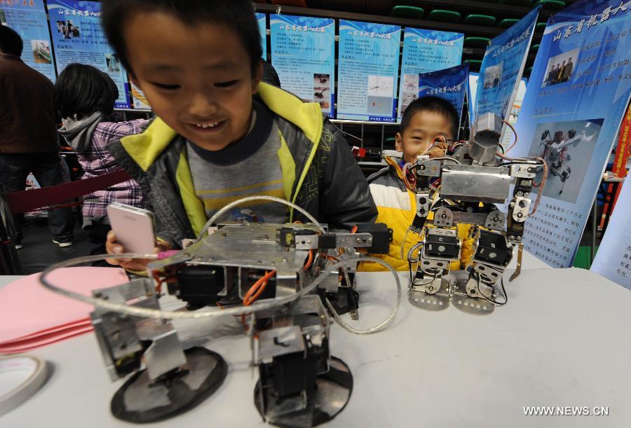Boys view robots in a robot show held in Qingdao University, Qingdao, east China's Shandong Province, Nov. 25, 2012. The robot show, the first kind of this exhibition in Shandong, showcased the latest achievement of robot-related technology, involving over 100 exhibits from home and abroad. (Xinhua/Guo Xulei) 