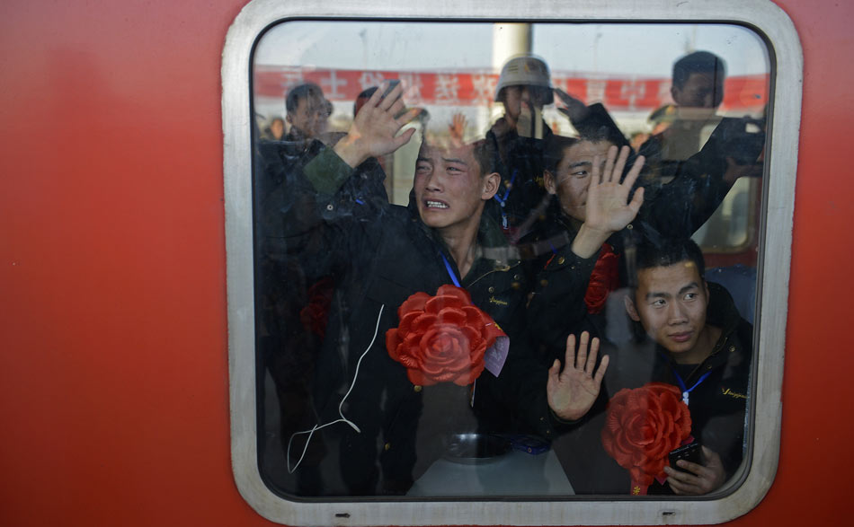 Veterans bid farewell to their comrades though windows on the train on Nov. 25, 2012. Thousands of veterans bid farewell to their camp, comrades and set foot on their way home that day. (Xinhua/Wang Peng)
