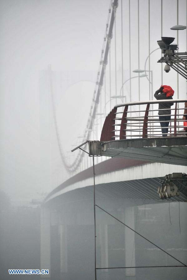 A citizen walks in the fog-shrouded Liuzhou City, southwest China's Guangxi Zhuang Autonomous Region, Nov. 25, 2012. (Xinhua/Li Hanchi) 