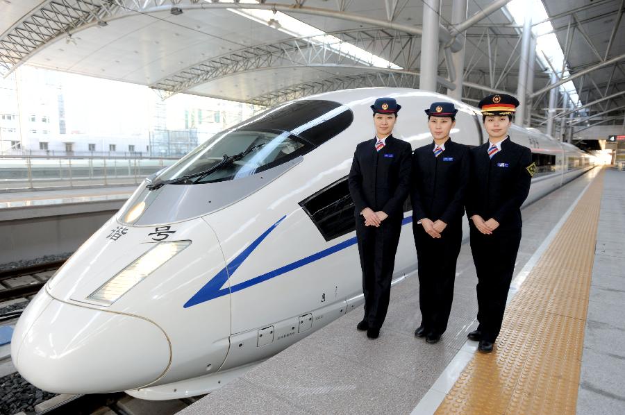 Attendants pose for photos next to a CRH bullet train which is to operate on the Harbin-Dalian High-Speed Railway in Shenyang, capital of northeast China's Liaoning Province, Nov. 26, 2012. The Shenyang Railway Bureau has launched training programmes for bullet train attendants who will be working on the Harbin-Dalian High-Speed Railway, scheduled to open on Dec. 1, 2012. The 921-km Harbin-Dalian High-Speed Railway is the first rail line in China's freezing high-latitude regions. (Xinhua/Zhang Wenkui) 