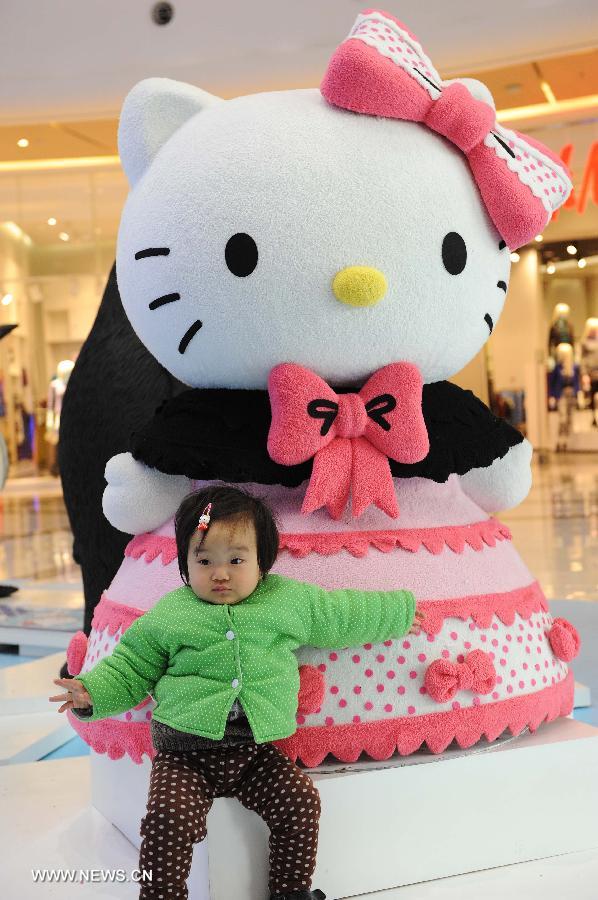A child poses for pictures in front of a Hello Kitty in the Joy City in east China's Shanghai Municipality, Nov. 26, 2012. A big Hello Kitty exhibition themed on Hello Kitty's exploration in the polar regions would last from Nov. 24, 2012 to Feb. 24, 2013 in Shanghai. (Xinhua/Lai Xinlin) 