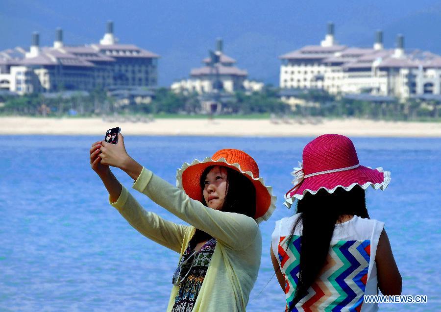 Two women take pictures of themselvs on Wuzhizhou Island in Sanya, a famous tourism city in south China's Hainan Province, Dec. 1, 2012. As Sanya has entered its tourist season, more tourists are seen here. (Xinhua/Wang Song)