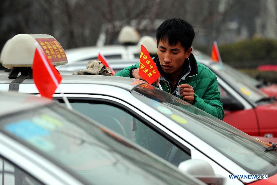 A taxi driver plants a red flag written with traffic safety information on his car to mark the country's first national day for road safety in Taiyuan, capital of north China's Shanxi Province, Dec. 2, 2012. (Xinhua/Fan Minda)