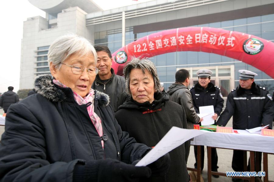 Citizens read materials on traffic safety knowledge during an event to mark the country's first national day for road safety in Heihe, northeast China's Heilongjiang Province, Dec. 2, 2012. (Xinhua/Ren Lihua)