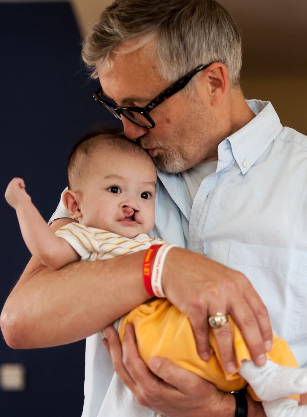 Tim Baker kisses a child born with cleft lip and palate at the Shepherd's Field in Tianjin, north China, May 29, 2012.(Xinhua/Zhang Chaoqun)