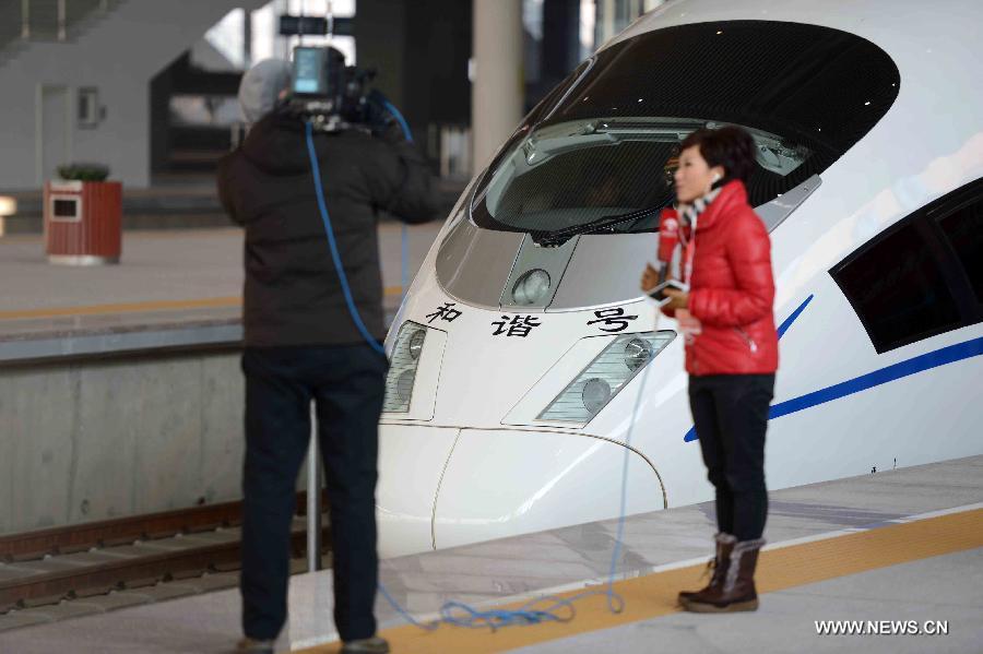 Reporters work in front of a high-speed train at the Harbin West Railway Station in Harbin, capital of northeast China's Heilongjiang Province, Dec. 1, 2012. (Xinhua/Wang Kai)