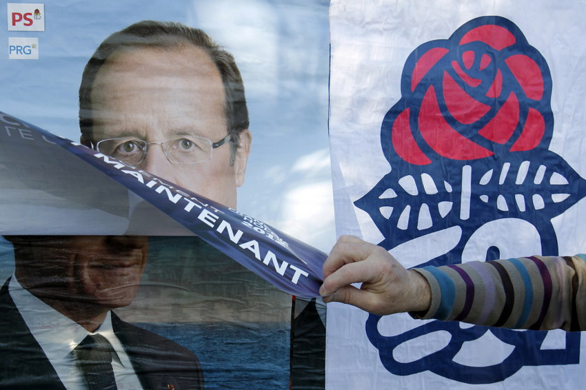 A France Social Party activist sticks the party candidate’s poster over the poster of Sarkozy on April 12, 2012. (Reuters /Stephane Mahe)