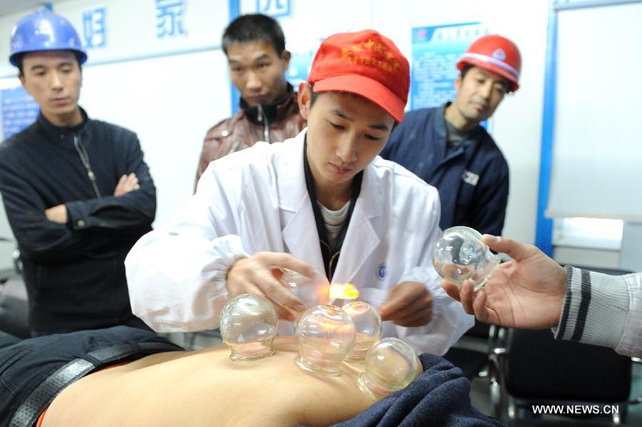 A volunteer from Anhui Chinese Traditional Medicine Institute implements cupping therapy on a migrant worker in Hefei, capital of east China's Anhui Province, Dec. 5, 2012. Many Chinese volunteers make their contributions to the society on Wednesday, to mark the International Volunteer Day, which is an international observance designated by the United Nations since 1985. (Xinhua/Liu Junxi) 