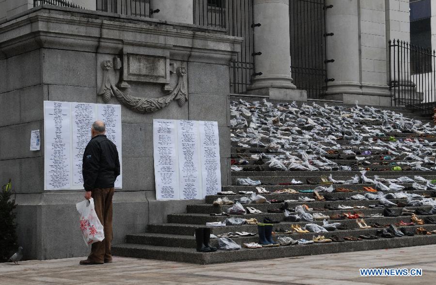 A man reads names of deceased women at annual Shoe Memorial on the steps of Vancouver Art Gallery in Vancouver, Canada, Dec. 6, 2012. December 6th is Canada's National Day of Mourning for women who have met with violent deaths. Shoes in bags represent dead women, and those without bags represent women who are alive but suffer from abuse. (Xinhua/Sergei Bachlakov)
