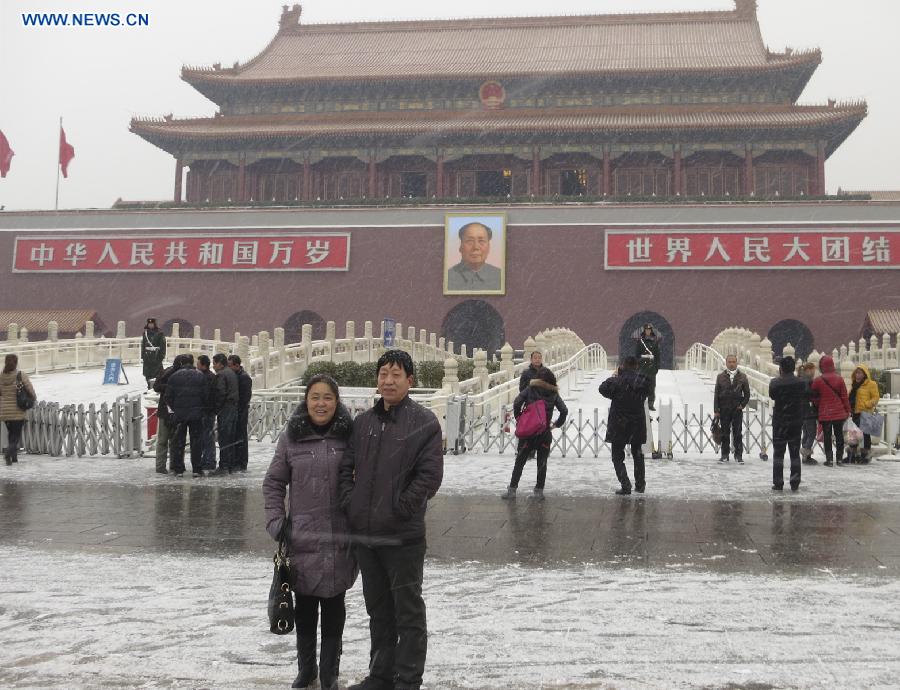 Two tourists pose for photos in snow at the Tian'anmen Square in Beijing, capital of China, Dec. 12, 2012. A snow hit China's capital city on Wednesday. (Xinhua/Lai Xiangdong) 