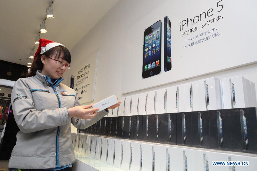 A salesperson counts the number of iPhone 5 cell phones to be sold in Binhai New Area in Tianjin, north China, Dec. 13, 2012. Apple iPhone 5 is scheduled to be released in Chinese mainland on Friday. (Xinhua)
