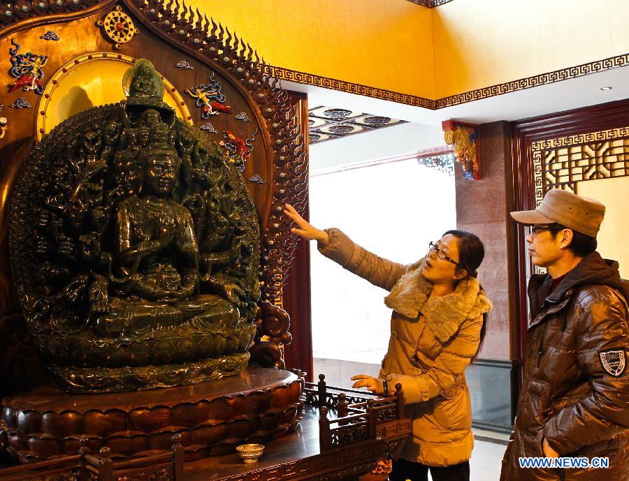 Gao Mei (L), the wife of Taiwanese sculptor Hung Fu-shou, introduces a jade sculpture portraying the Thousand-Handed Avalokitesvara to a visitor in a gallery of their company in Taizhou, east China's Jiangsu Province, Dec. 8, 2012. Hung Fu-shou and Gao Mei, who came from Nanjing City of Jiangsu Province, first met each other 18 years ago and got married two years later. (Xinhua/Xue Dongmei)