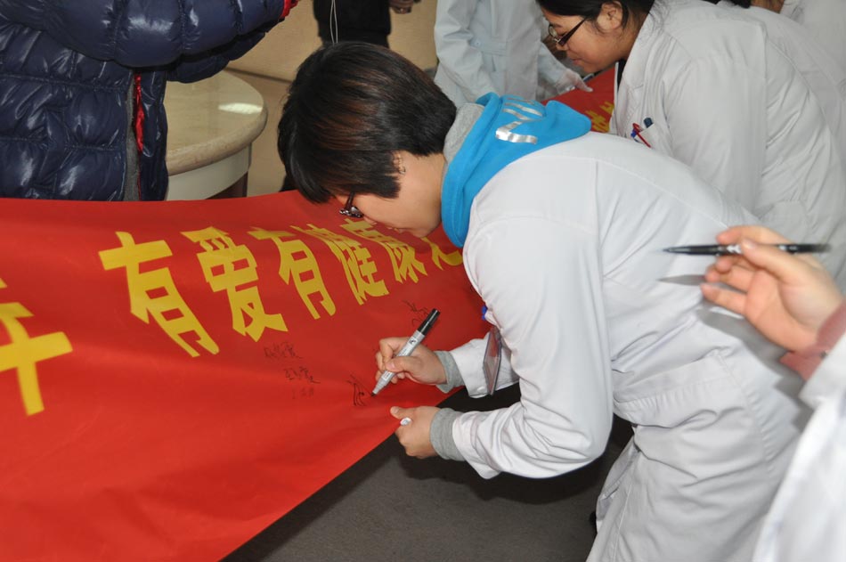 A medical staff of Beijing Ruijing Diabetes Hospital writes down his name on the banner on Dec. 12, 2012, as a way of making a commitment to provide better medical service. The campaign for providing patient-oriented medical service has been officially launched in the hospital on Wednesday afternoon.  (Photo/People's Daily Online) 