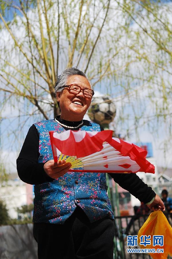 A senior woman perfoms fans dance in the park in Xining.(Xinhua Photo)