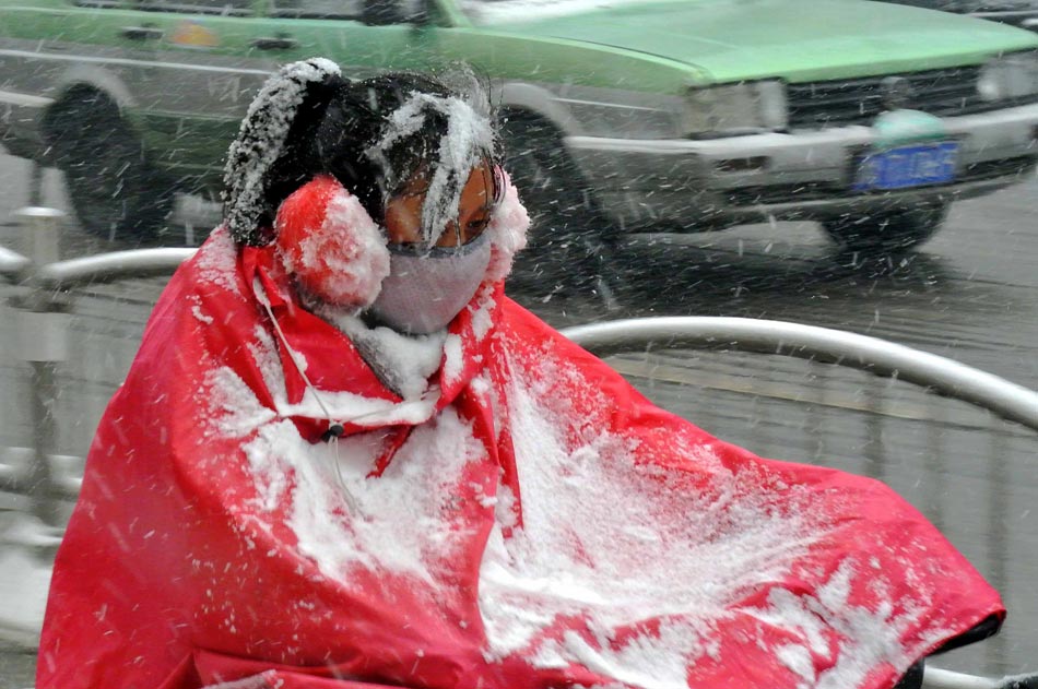 A woman rides in snow in Zhengzhou, capital of central China's Henan Province, on Dec. 13, 2012. (Xinhua/Wang Song) 