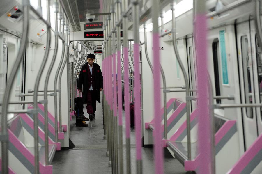 A staff member inspects the train of Wuhan Subway Line No.2 in Wuhan, capital of central China's Hubei Province, Dec. 14, 2012. Subway Line No.2 is the first subway line of the city, also the first subway line across the Yangtze River. The construction of the project started in 2006. It is expected to be put into trial operation on Dec. 28. (Xinhua/Hao Tongqian) 