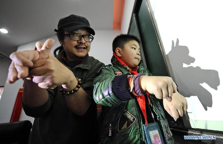 Shen Xiao (L), a hand shadow play artist, teaches a student to play hand shadow at Ziyan Primary School in Mianzhu, a city in southwest China's Sichuan Province, Dec. 14, 2012. Shen has been teaching students at the primary school every week since last September. (Xinhua/Xue Yubin) 
