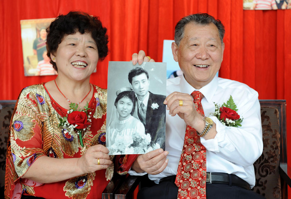 Tan Enxiang(Right) and Peng Yuehua show their wedding photo to relatives and friends on a party held to celebrate Tan and Peng’s 50th marriage anniversary, Oct. 1, 2012. (Xinhua/Sun Sen)