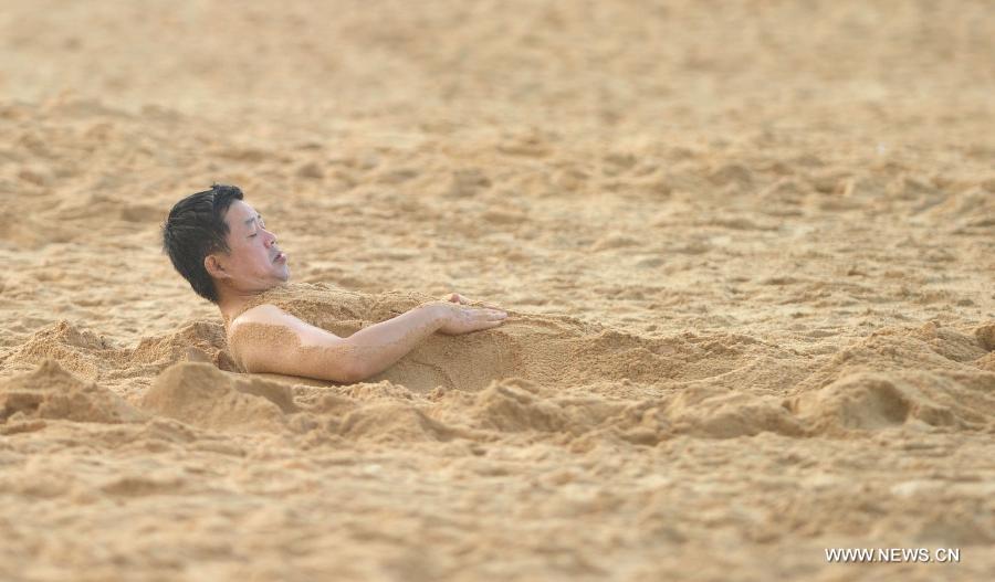 A man buries himself in the sand on the beach in Haikou, capital of south China's Hainan Province, Dec. 21, 2012. Thursday marks the Dongzhi Festival, or Winter Solstice. Contrary to people in north China who are expected to welcome the coldest winter days, people in Hainan still enjoy the warm climate. (Xinhua/Zhao Yingquan) 