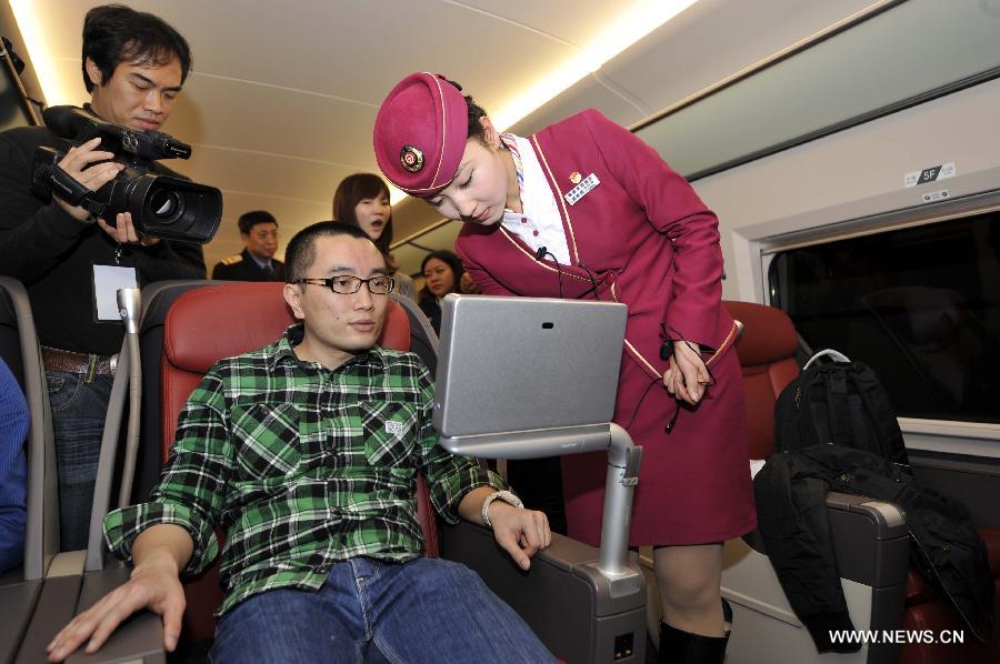 A stewardess adjusts a television set for a passenger in a business class carriage of G80 express train during a trip to Beijing, capital of China, Dec. 22, 2012.