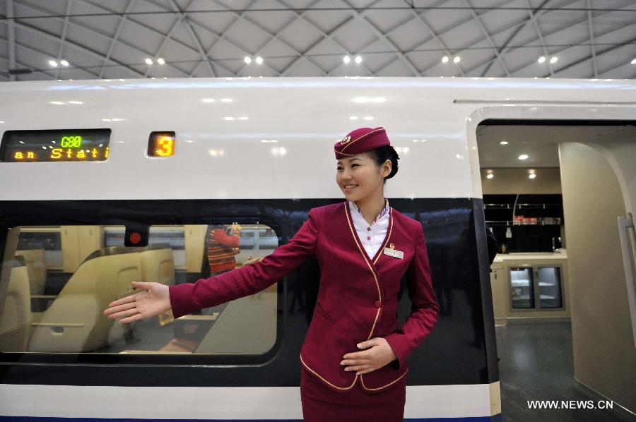 A stewardess waits for passengers by the G80 express train at Shijiazhuang Railway Station during a trip to Beijing, capital of China, Dec. 22, 2012.